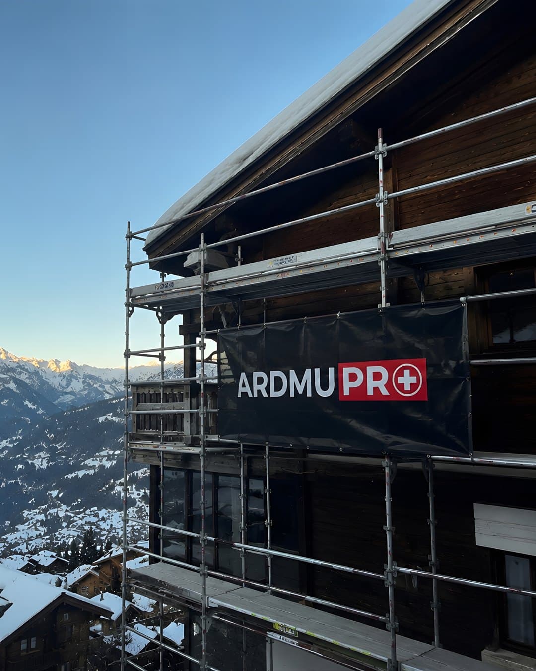 Chantier de façade ARDMUPRO sur un chalet alpin, bâche brandée face aux Alpes